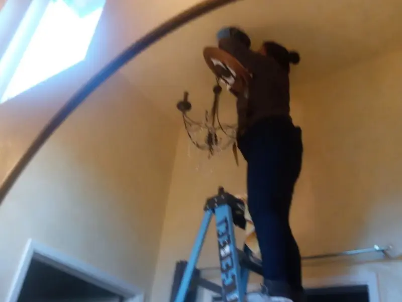Electrician installing a chandelier in a Barbecue residence